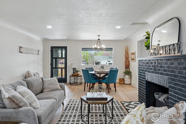 living area with a textured ceiling, a notable chandelier, wood finished floors, and a fireplace