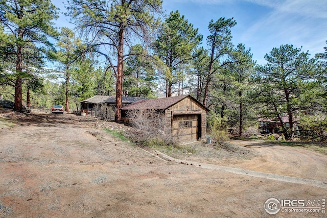 exterior space featuring a garage and dirt driveway
