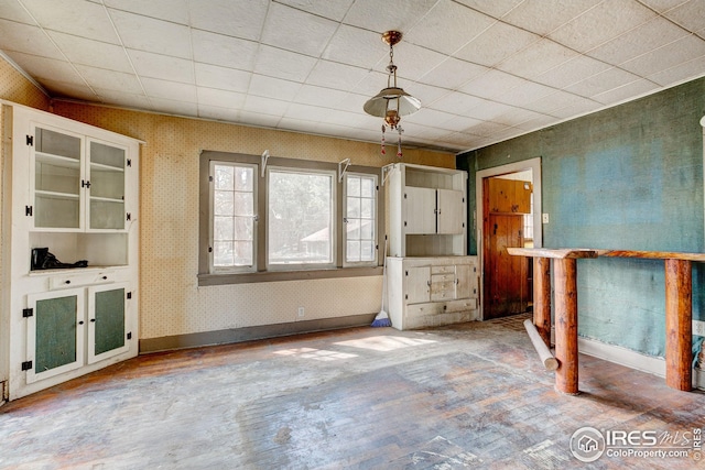 unfurnished living room with baseboards, wood finished floors, and wallpapered walls