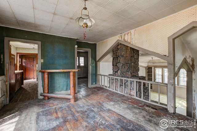 unfurnished living room featuring wallpapered walls and hardwood / wood-style floors