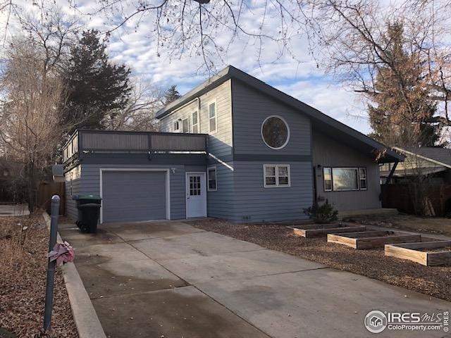 view of front of home with an attached garage, concrete driveway, and a garden