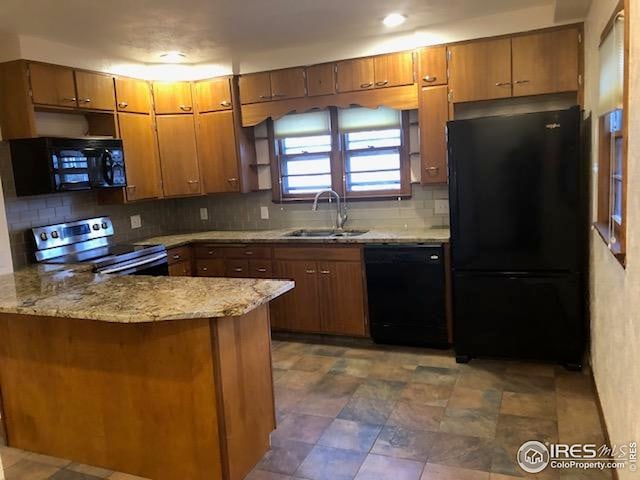 kitchen featuring a peninsula, brown cabinetry, a sink, and black appliances