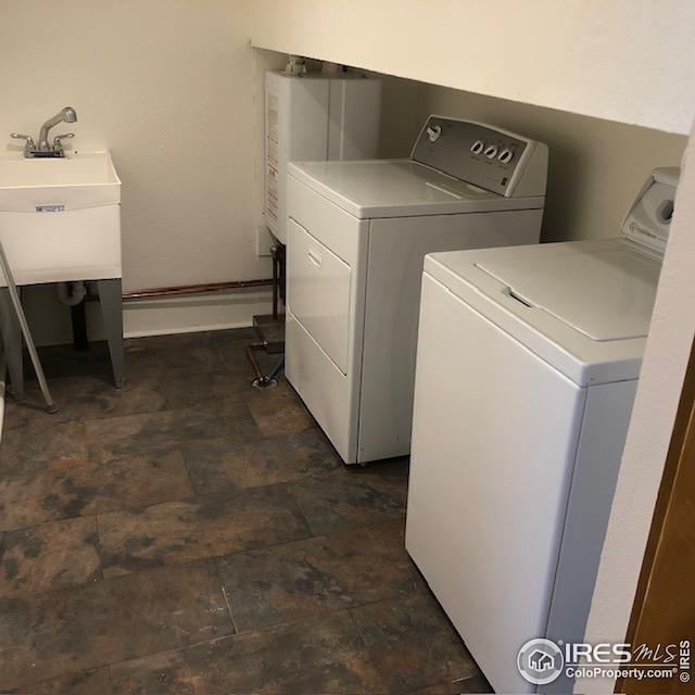 laundry room with a sink, water heater, laundry area, and independent washer and dryer