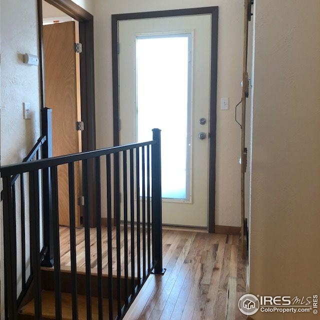 interior space featuring wood-type flooring, baseboards, a textured wall, and an upstairs landing