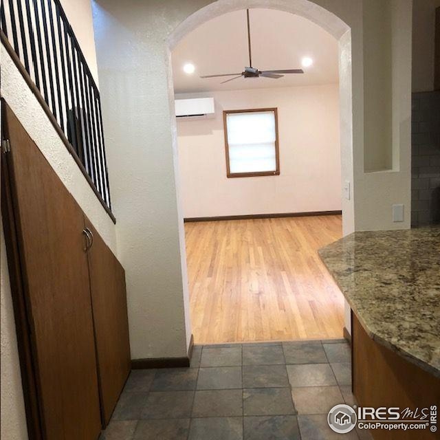 corridor with baseboards, arched walkways, and a wall mounted AC