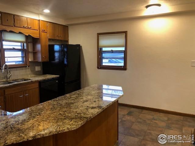kitchen with decorative backsplash, brown cabinets, a sink, baseboards, and black appliances