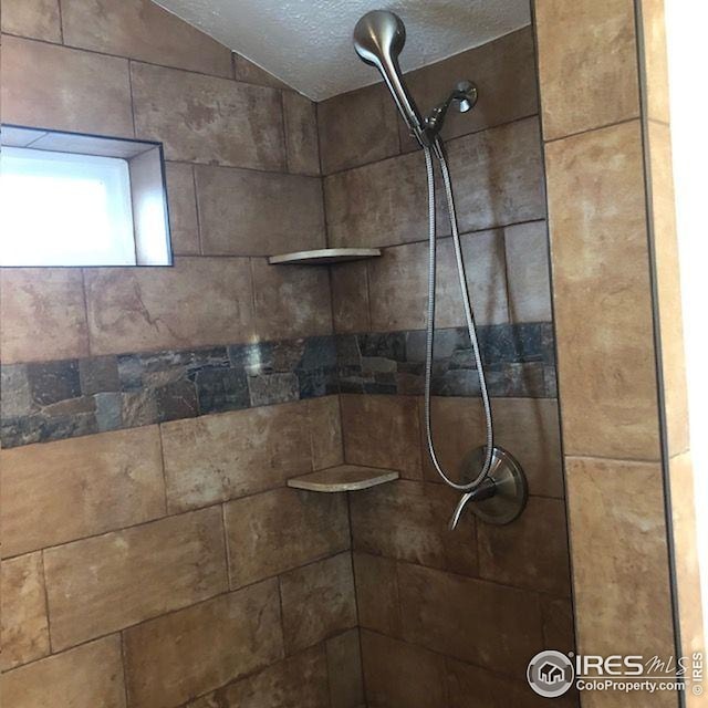 interior details featuring a tile shower and a textured ceiling