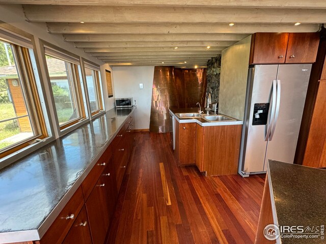 kitchen with dark wood-style flooring, stainless steel counters, a sink, beamed ceiling, and stainless steel appliances