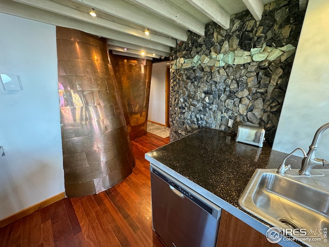 kitchen with stainless steel dishwasher, dark countertops, beamed ceiling, a sink, and dark wood finished floors