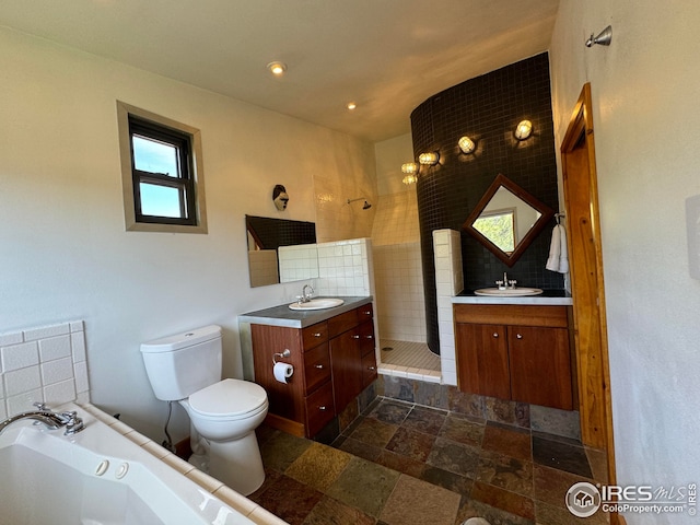 bathroom with vanity, stone tile floors, toilet, a tub, and a shower stall