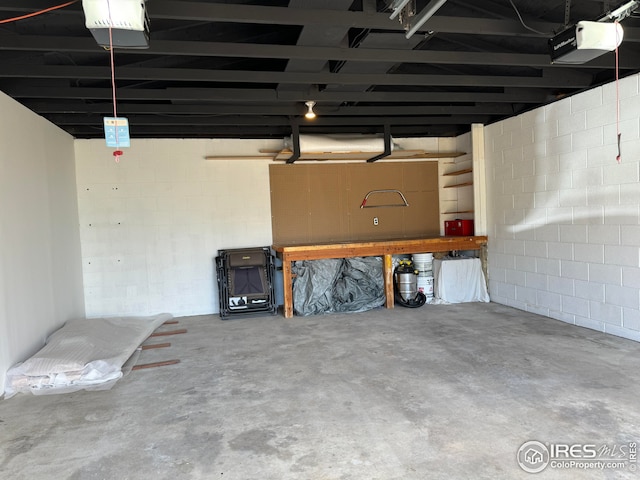 garage featuring concrete block wall and a garage door opener