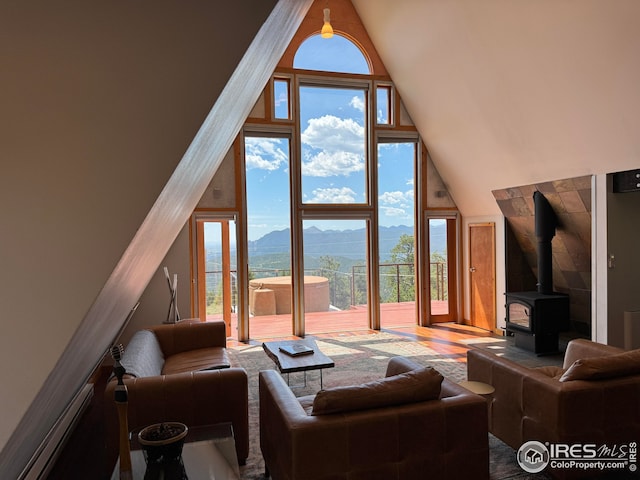 living room featuring high vaulted ceiling, a mountain view, a wealth of natural light, and a wood stove