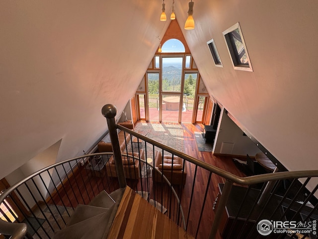 stairway featuring wood-type flooring and high vaulted ceiling