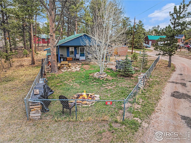 view of yard with a porch, dirt driveway, an outdoor fire pit, and fence