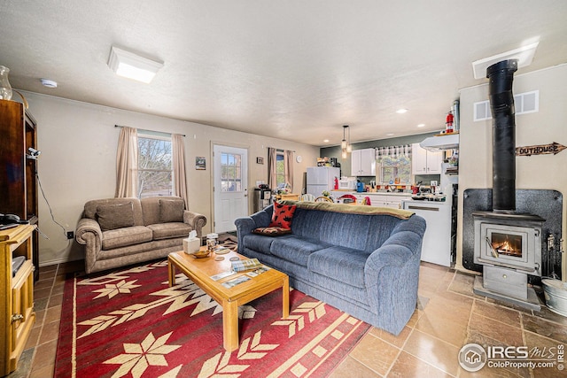 living area featuring recessed lighting, visible vents, and a wood stove
