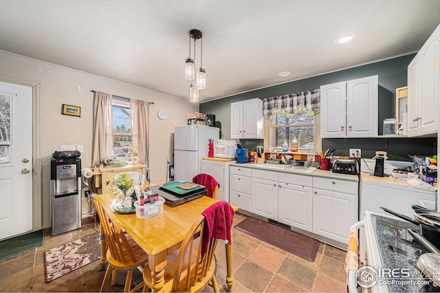 kitchen with hanging light fixtures, a sink, light countertops, white appliances, and white cabinetry