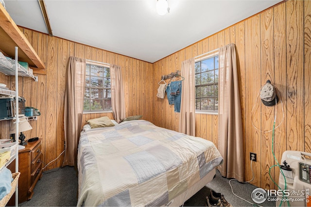 bedroom with multiple windows, carpet, and wood walls