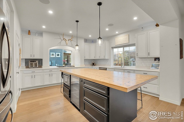 kitchen featuring arched walkways, white cabinets, a sink, wood counters, and appliances with stainless steel finishes