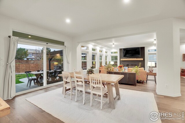 dining area featuring light wood-style floors, recessed lighting, and a fireplace