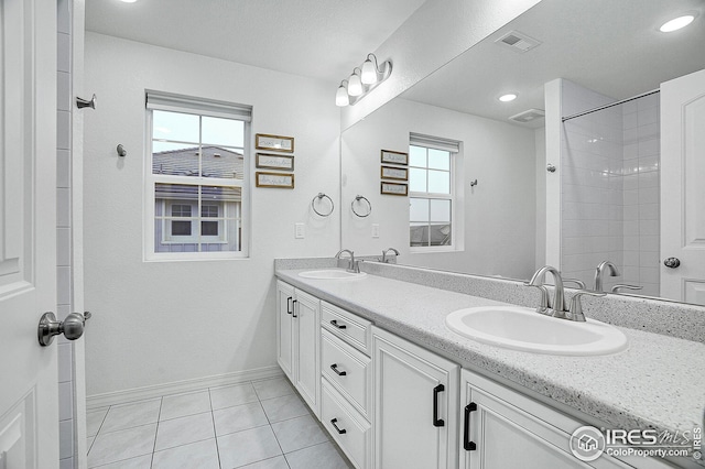 bathroom with tile patterned flooring, a sink, baseboards, and double vanity