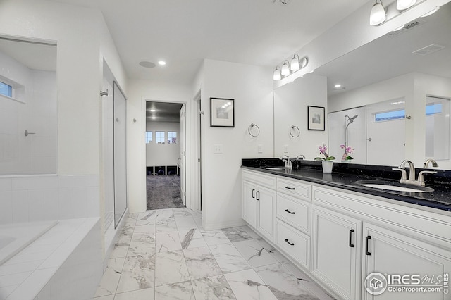 full bath with a sink, a shower stall, marble finish floor, and visible vents