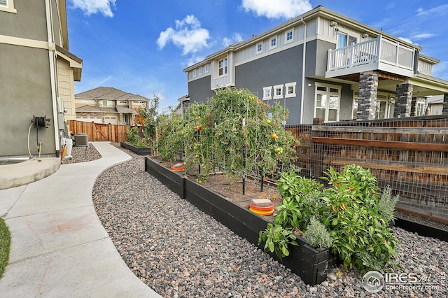 view of side of property with fence, stucco siding, a garden, and central AC