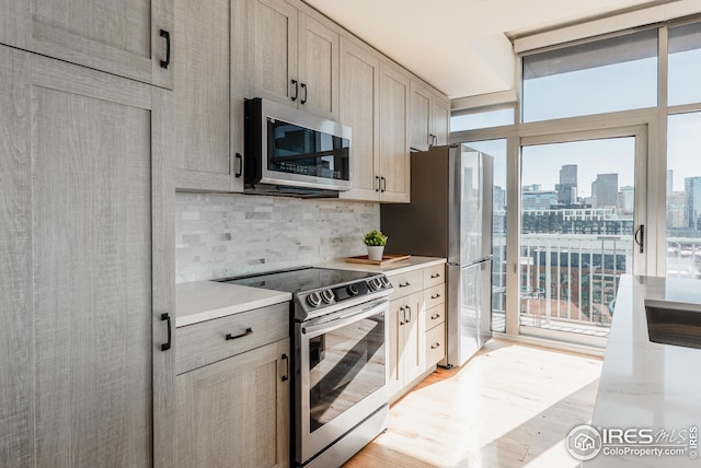 1700 Bassett St Unit 1808, Denver, CO 80202 - kitchen with light wood-type flooring, light countertops, a city view, backsplash, and stainless steel appliances