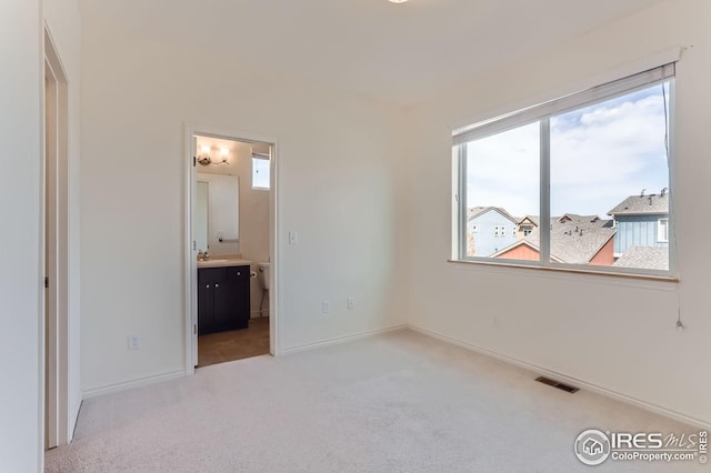 unfurnished bedroom featuring visible vents, a sink, carpet, and multiple windows