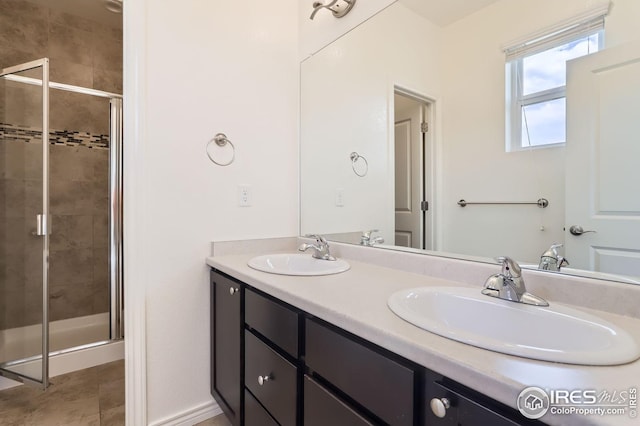 bathroom with double vanity, a shower stall, and a sink