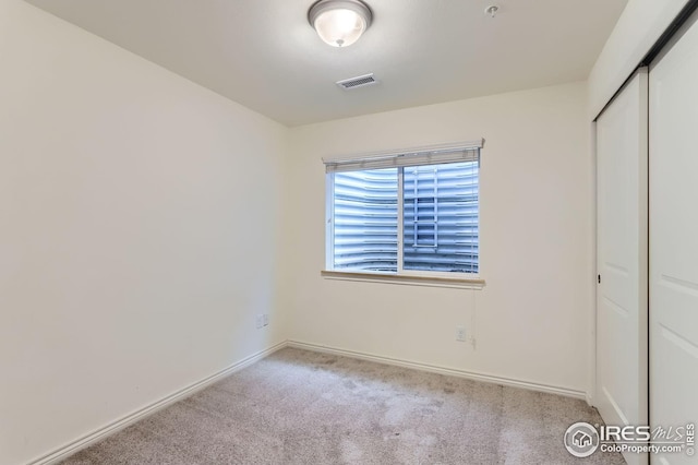 unfurnished bedroom featuring carpet floors, baseboards, a closet, and visible vents