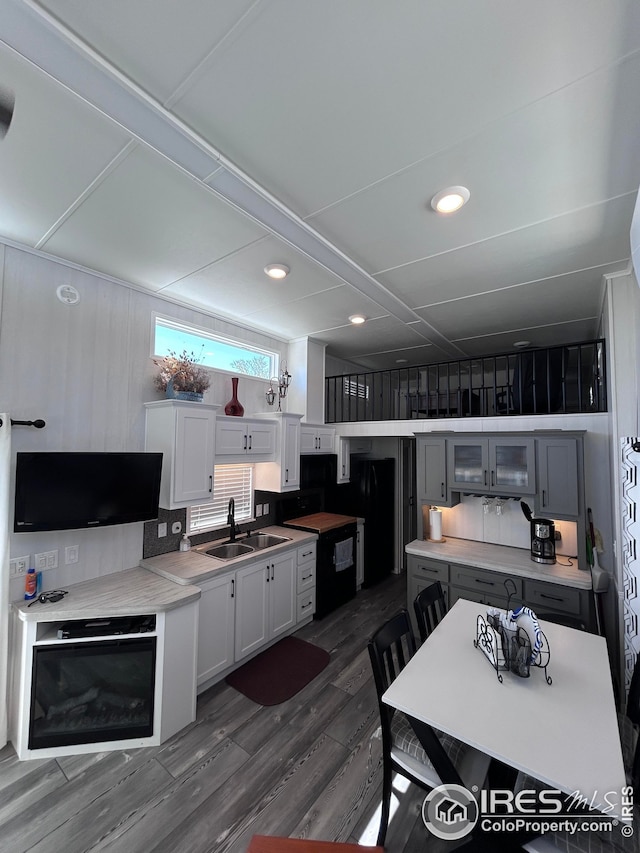 kitchen with white cabinets, a sink, dark wood finished floors, stove, and glass insert cabinets