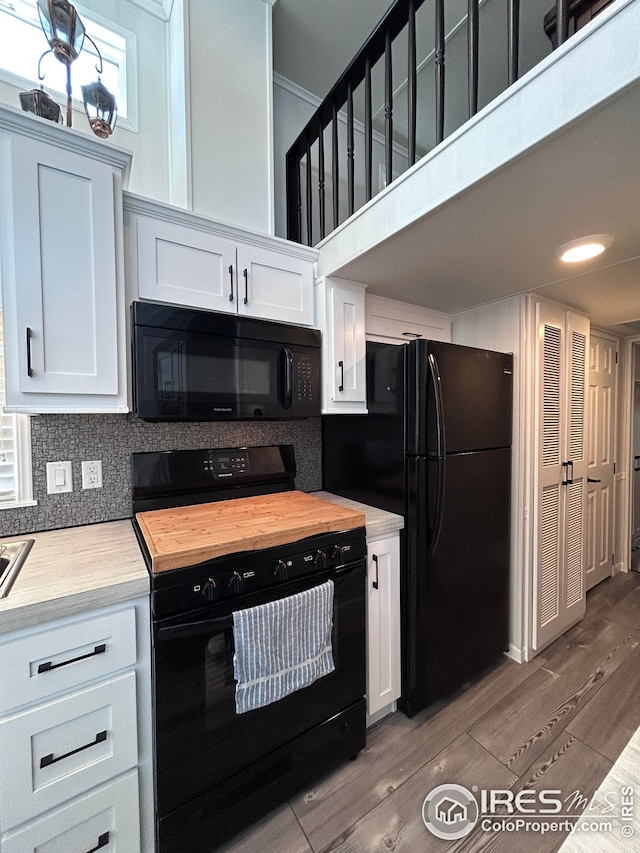 kitchen with light wood finished floors, white cabinetry, decorative backsplash, butcher block counters, and black appliances