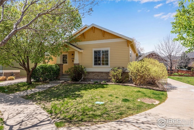 view of front of house with brick siding, driveway, and a front yard