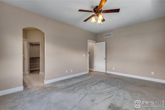 unfurnished bedroom featuring arched walkways, baseboards, carpet, and visible vents