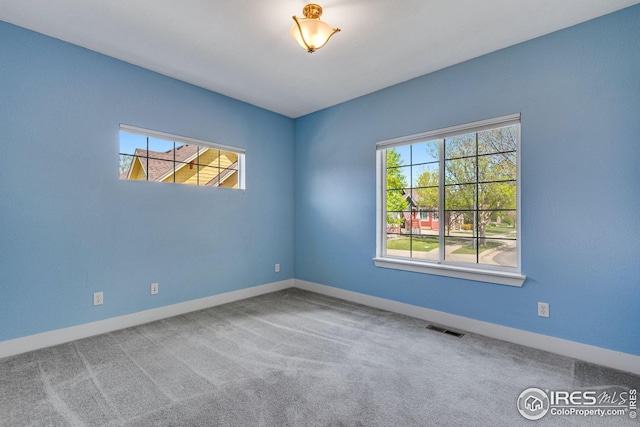 carpeted spare room featuring baseboards and visible vents