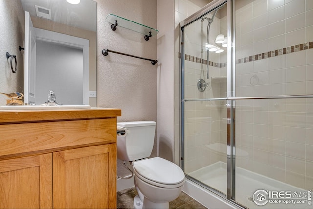 full bathroom with a textured wall, a stall shower, toilet, and visible vents