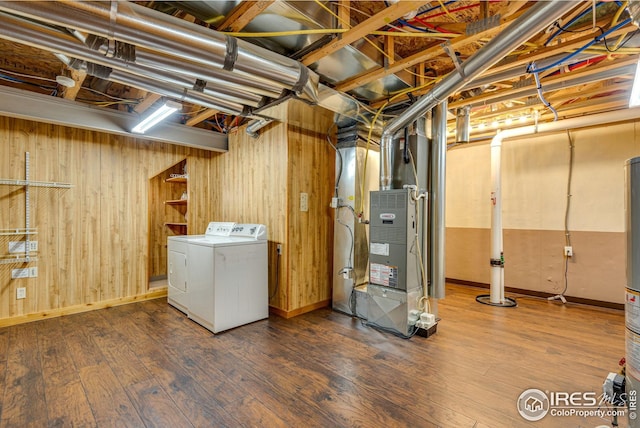unfinished basement with independent washer and dryer, wooden walls, baseboards, heating unit, and wood finished floors