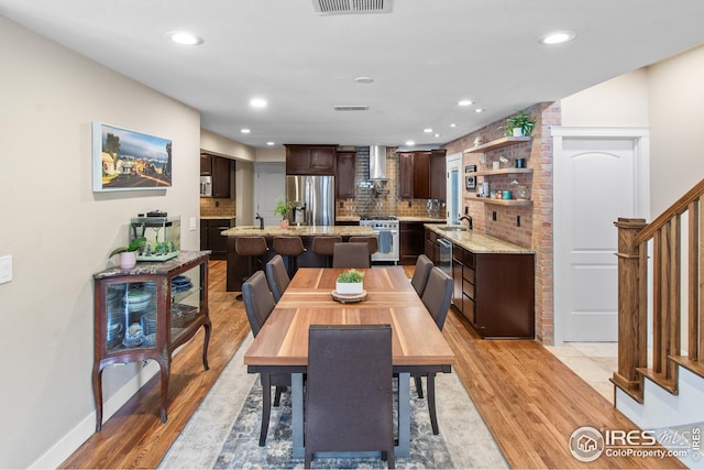dining room with recessed lighting, light wood finished floors, and stairway