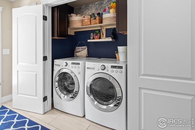 clothes washing area featuring cabinet space, light tile patterned flooring, and washer and clothes dryer