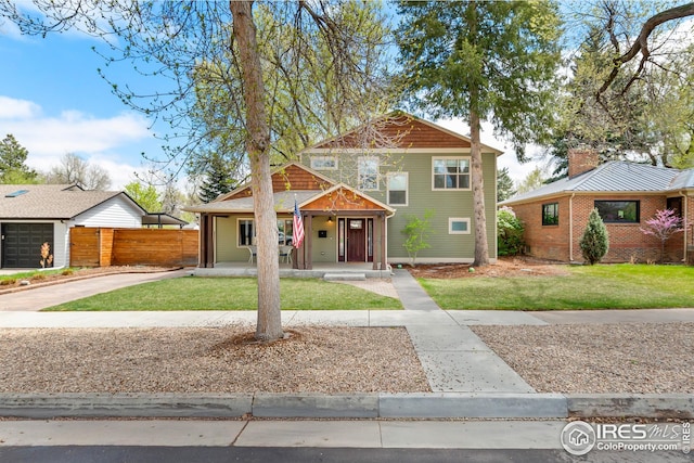 view of front facade with fence, a porch, driveway, and a front yard