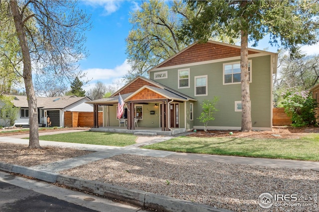view of front facade featuring fence, covered porch, a front yard, and concrete driveway