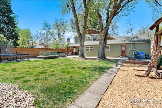 view of yard with fence, a patio area, and a trampoline