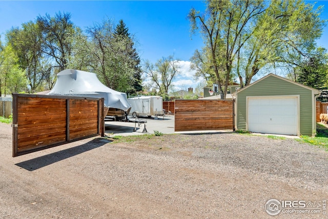 detached garage with fence and dirt driveway