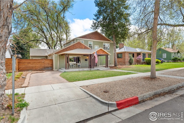 view of front of property featuring fence, a front lawn, a porch, and driveway