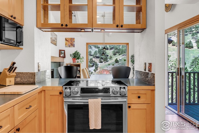 kitchen featuring stainless steel range with electric stovetop, black microwave, light brown cabinets, and glass insert cabinets