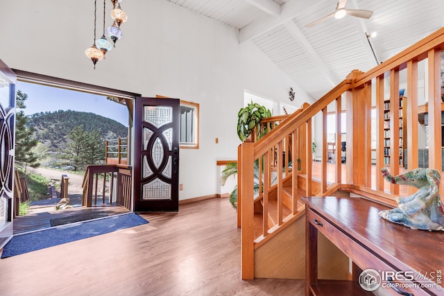 foyer with high vaulted ceiling, stairs, baseboards, wood finished floors, and a mountain view