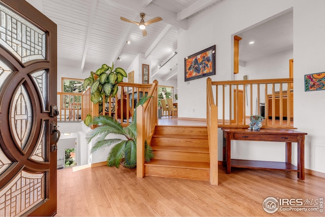 entrance foyer with beam ceiling, ceiling fan, wood finished floors, and stairway