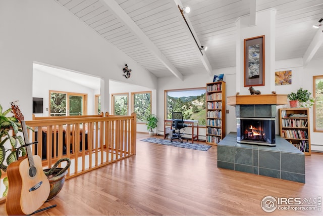 living room featuring beam ceiling, wood ceiling, a fireplace, and wood finished floors