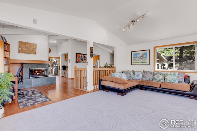 living room with vaulted ceiling, wood finished floors, and a tile fireplace