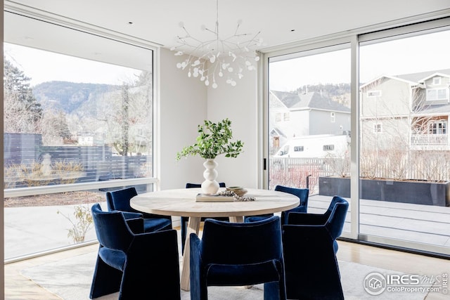 dining area featuring a wall of windows, a mountain view, wood finished floors, and a notable chandelier